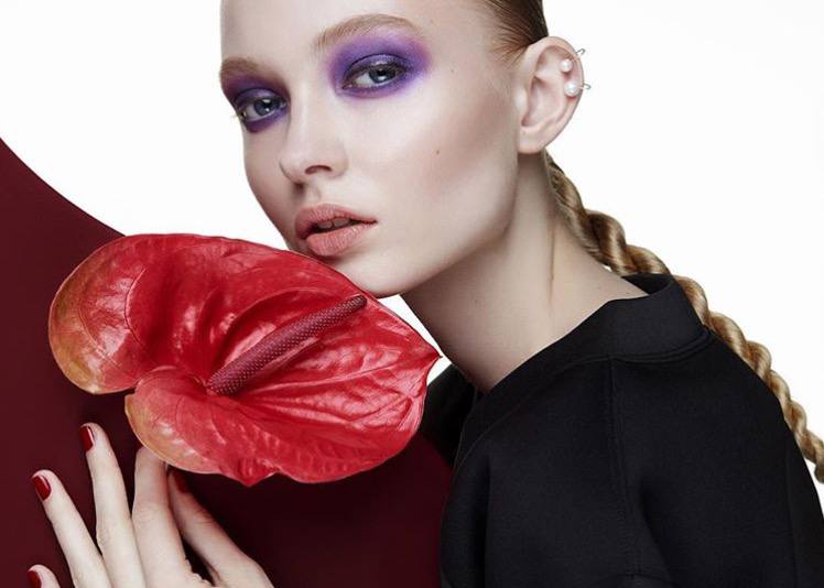 A red anthurium flower held close to the face