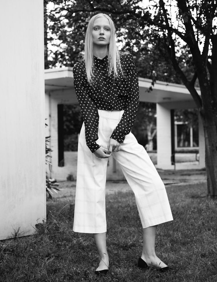 Nikita Lauffer in a black and white polka-dot blouse and white culottes, black and white