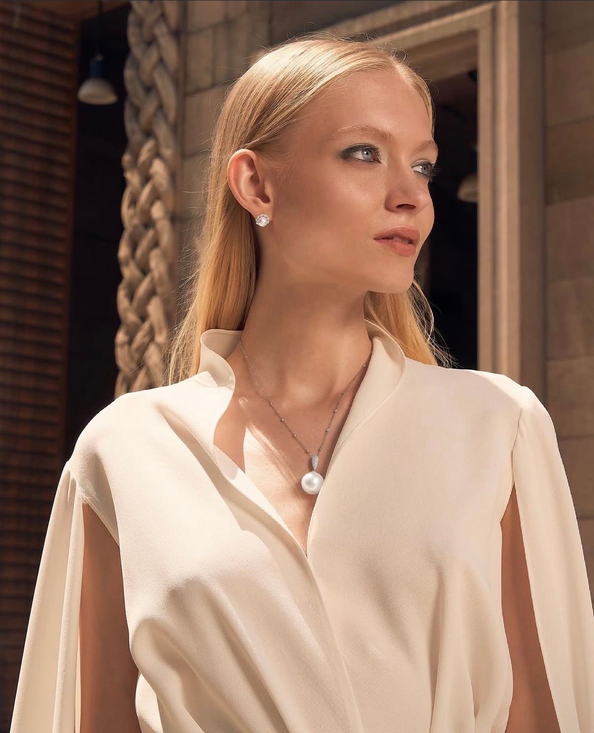 Nikita Lauffer in a cream blouse with a pendant, in profile
